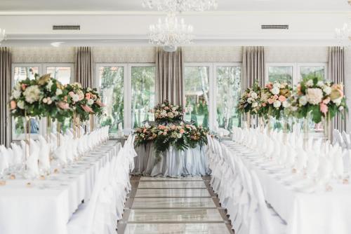 a row of tables with white chairs and flowers at BURSZTYN - BERNSTEIN SPA & Wellness in Dąbki