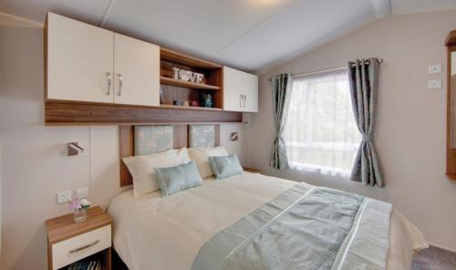 a bedroom with a large bed and a window at Par Sands Coastal Holiday park in Par