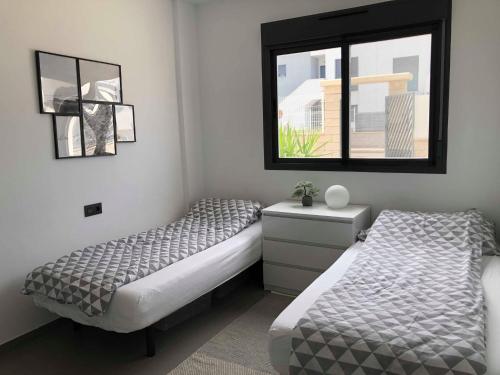 a bedroom with two beds and a window at Oasis Beach 1, La Zenia in Playas de Orihuela