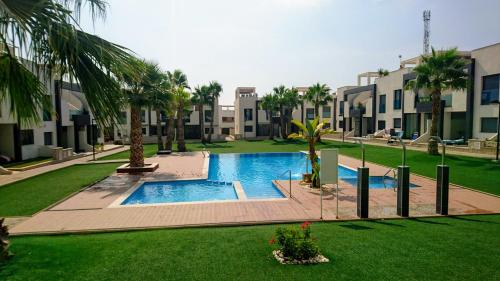 una piscina en un patio con palmeras y edificios en Oasis Beach 1, La Zenia, en Playas de Orihuela