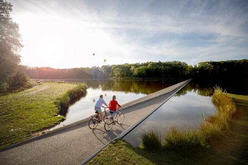 dos personas montando bicicletas en un puente sobre un río en Huis Berenbroek en Genk