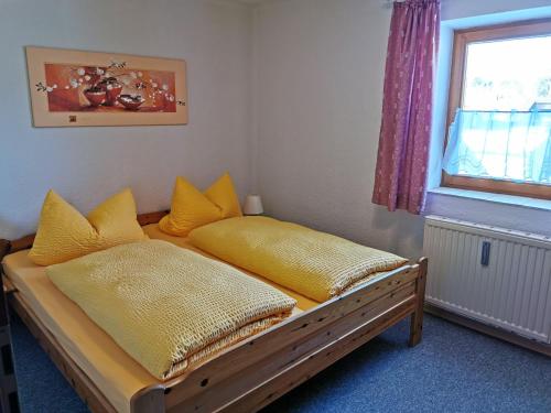 a bedroom with a bed with yellow pillows and a window at Haus Haidweg Wohnung 4 in Haidmühle