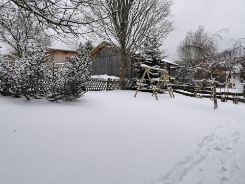 a yard covered in snow with a swing at Ferienhaus-Haidweg-Wohnung-3 in Haidmühle