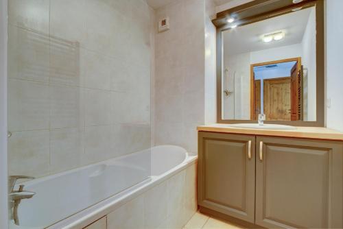 a bathroom with a tub and a sink and a mirror at Slalom Apartment - Very Town Centre - Snow and Trek - Morzine in Morzine