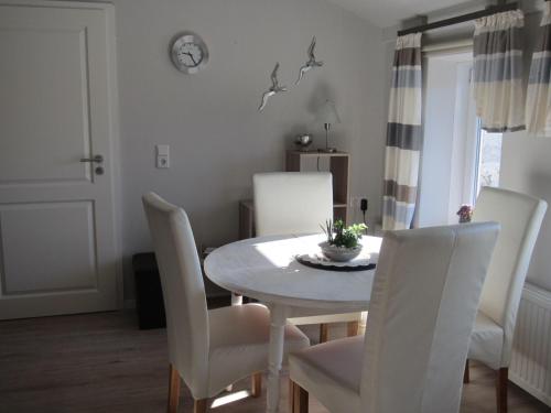 comedor con mesa blanca y sillas blancas en Ferienwohnung-England, en Nordstrand