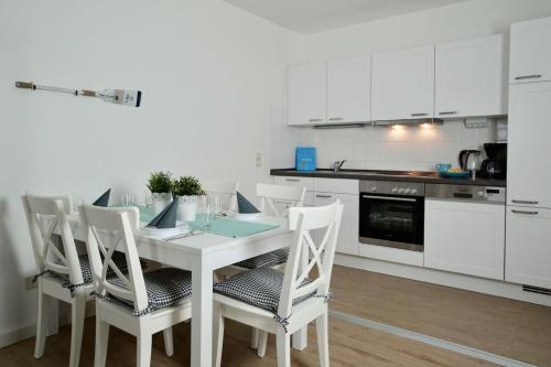 eine weiße Küche mit einem weißen Tisch und Stühlen in der Unterkunft  Ferienappartement Jasmund 20 in Ostseebad Sellin
