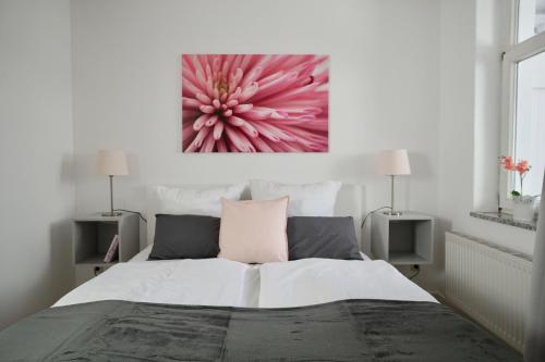 オストゼーバート・ゼリンにあるFerienappartement-Jasmund-19のピンクの花の絵が飾られたベッドルーム