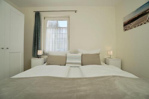 a large white bed in a bedroom with a window at Ferienappartement-Moenchgut-01 in Ostseebad Sellin