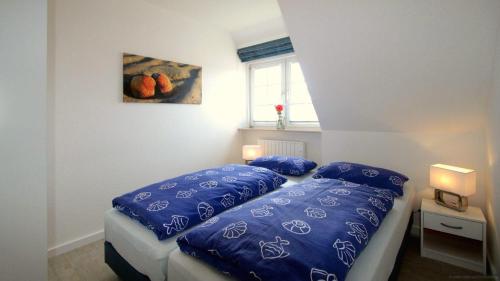 a bedroom with a bed with blue pillows and a window at Gaestehaus-Meene-Menten-Wohnung-MM-6 in Süderhöft