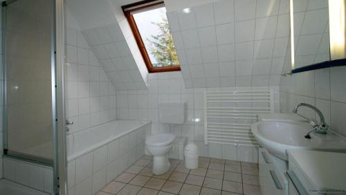 a white bathroom with a toilet and a sink at Gaestehaus-Meene-Menten-Wohnung-MM-6 in Süderhöft