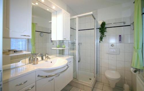 een witte badkamer met een wastafel en een douche bij Gaestehaeuser-Heidehof-Wohnung-5 in Süderhöft