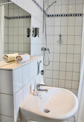 a white bathroom with a sink and a shower at Parkhotel Viktoria in Velten