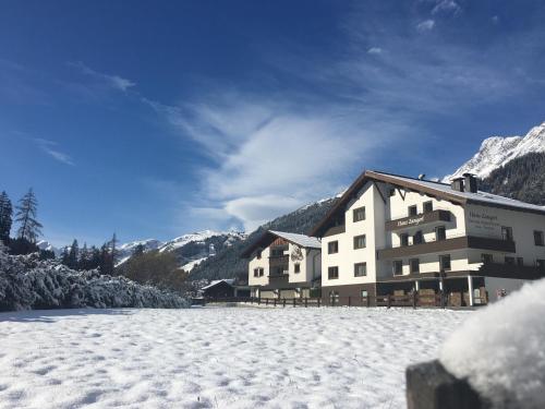 un grand bâtiment dans la neige avec des montagnes en arrière-plan dans l'établissement Haus Zangerl, à Sankt Anton am Arlberg