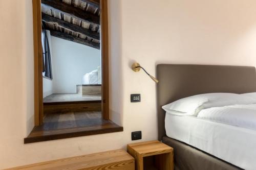 a bedroom with a bed and a mirror at Curt di Clement Eco Mobility Hotel in Tirano