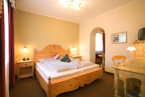 a bedroom with a bed and a desk in a room at PALMENGARTEN Hotel Gstör in Lagundo