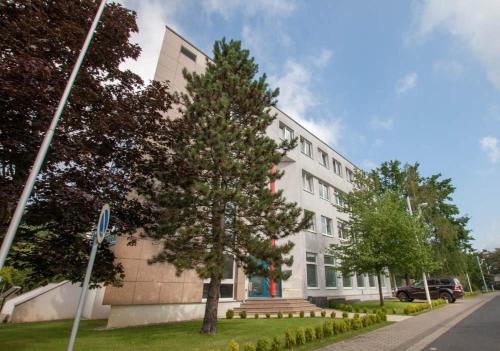 a white building with a tree in front of it at Parkhotel Viktoria in Velten