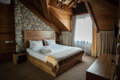 - une chambre avec un grand lit et un mur en pierre dans l'établissement Alpen Park, à Togliatti