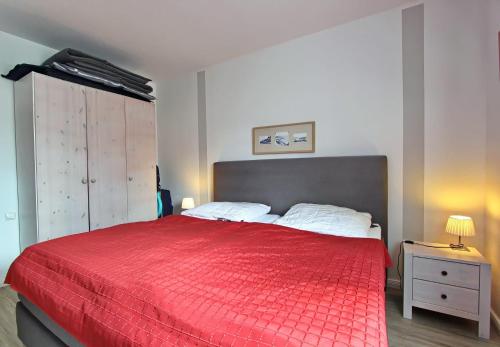 ein Schlafzimmer mit einem roten Bett mit einer roten Decke in der Unterkunft Sternbild in Hörnum