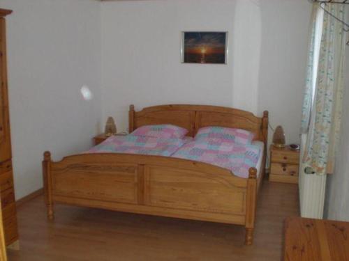 ein Schlafzimmer mit einem Holzbett in einem Zimmer in der Unterkunft Ferienwohnung Marita in Carolinensiel