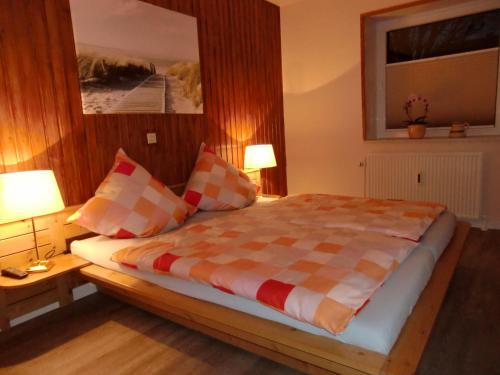 een slaapkamer met een bed met een geruite deken en 2 lampen bij Traumhafte-Ferienwohnung-Kaethi in Flensburg