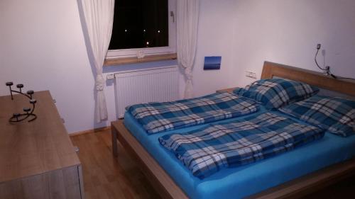 a bedroom with a bed with a blue comforter and a window at Ferienwohnung-Burgblick-in-Neuravensburg in Haggen
