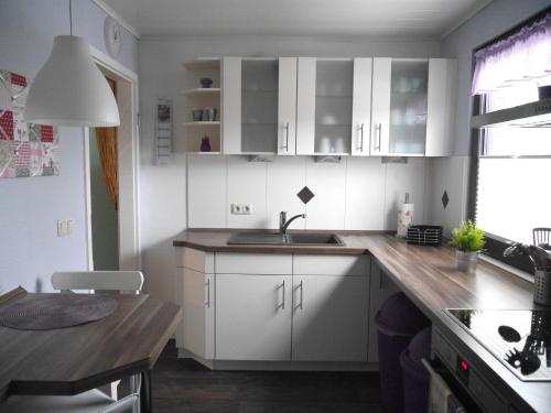 a kitchen with white cabinets and a wooden counter top at Ferienwohnung-Bullerby in Barkelsby