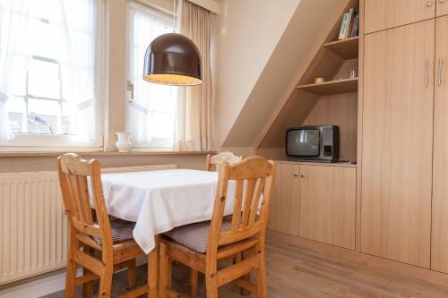 uma sala de jantar com mesa e cadeiras e uma televisão em Steinmannstr-53-Wohnung-OG em Westerland