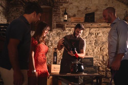 a group of people standing around a table with a bottle of wine at Castello di Bossi in Castelnuovo Berardenga