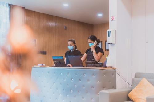 two women wearing face masks at a desk with laptops at Casa Retreat in Hulhumale