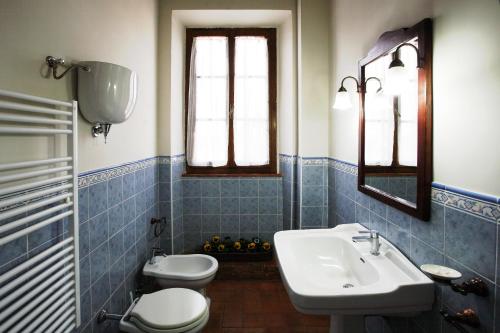 bagno piastrellato blu con lavandino e servizi igienici di Agriturismo Le Stringaie a Montepulciano Stazione