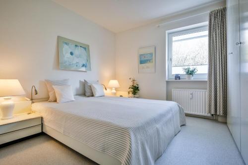 Un dormitorio blanco con una cama grande y una ventana en Appartement-Riva, en Wenningstedt