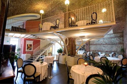 un restaurant avec des tables et des chaises blanches et un escalier dans l'établissement Hotel Cascina Di Corte, à Venaria Reale