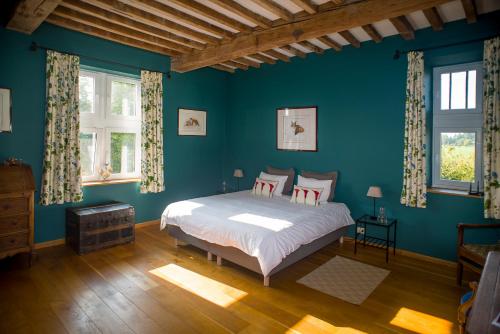 a blue bedroom with a bed and two windows at La tour de la Chapelle in Couthuin
