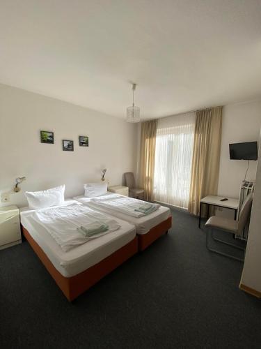 a hotel room with two beds and a desk at Hotel Seehaus in Horn-Bad Meinberg