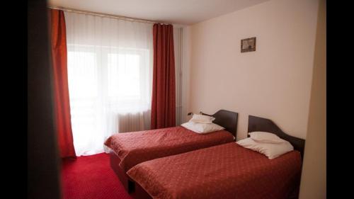 two beds in a hotel room with a window at Cristal Sinaia in Sinaia