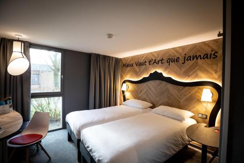 a hotel room with two beds and a sign on the wall at ibis Styles Douai Gare Gayant Expo in Douai