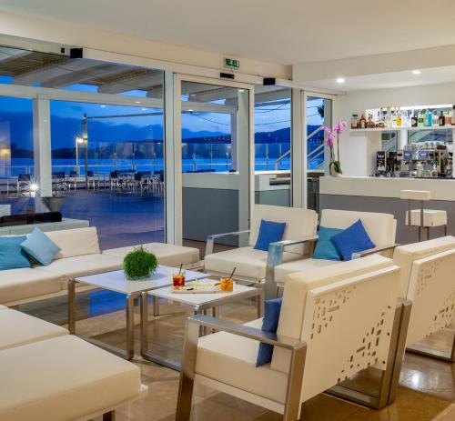 a living room with white furniture and a view of the ocean at El Faro Hotel & Spa in Porto Conte