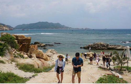 a group of people walking on a beach at Hoang Son Hotel in Nha Trang