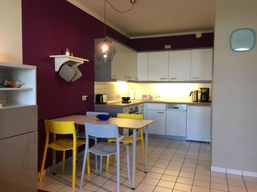 a kitchen with yellow chairs and a wooden table at 50 m zum Strand - App Strandhuepfer - Saisonstrandkorb inklusive in Timmendorfer Strand