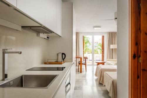 een witte keuken met een wastafel en een bank bij Apartments Parque Santiago IV in Playa de las Americas