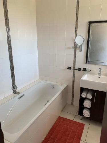 Baño blanco con bañera y lavamanos en Leighton Court, en Newcastle