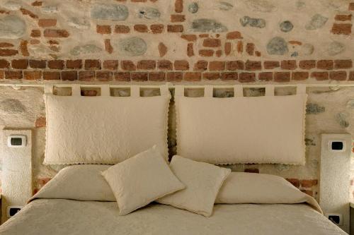 a bed with two pillows and a brick wall at Hotel Cascina Di Corte in Venaria Reale