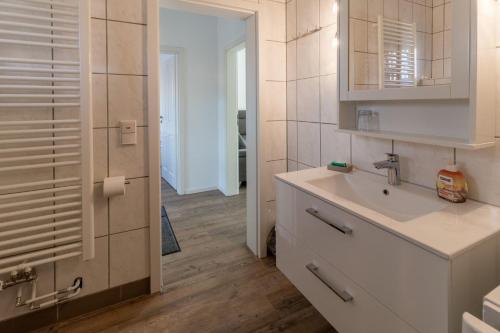 Baño blanco con lavabo y espejo en Ferienwohnung-in-Luebesse, en Lübesse