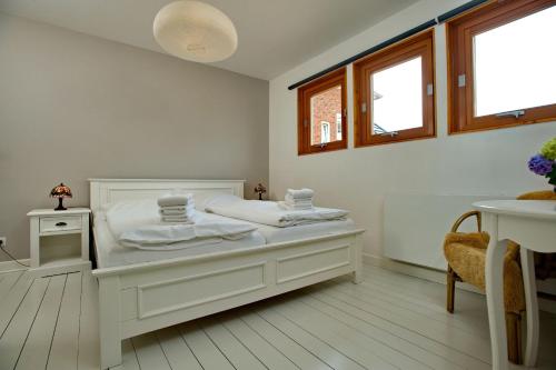 Un dormitorio blanco con una cama y dos ventanas. en Bungalow-L, en Westerland