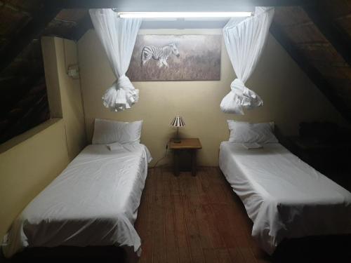 a room with two beds and a picture of a zebra at Pumusa Bushcamp in Hluhluwe