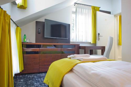 a bedroom with a tv and a bed with yellow curtains at WISŁA Cechini in Krynica Zdrój