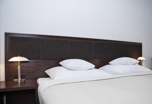 a large bed with white pillows and a wooden headboard at InterHotel in Wrocław