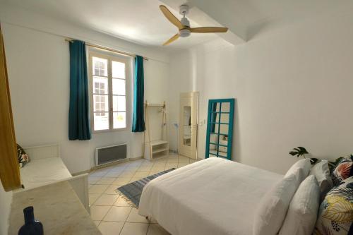 Old Town Antibes Apartment في أنتيب: غرفة نوم بسرير ومروحة سقف