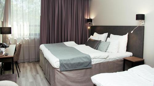 サロにあるOriginal Sokos Hotel Rikala Saloのベッド2台とデスクが備わるホテルルームです。