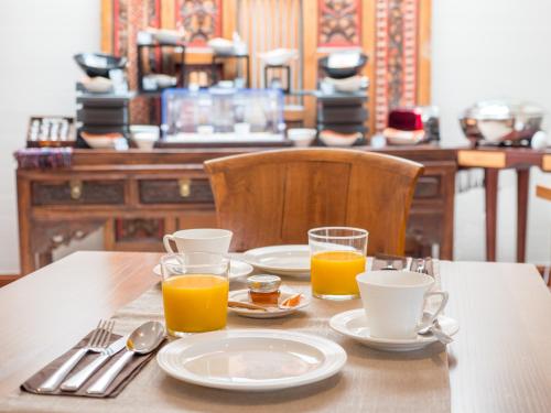 einen Tisch mit Teller und Gläsern Orangensaft in der Unterkunft Villa Kerasy Hotel Spa in Vannes